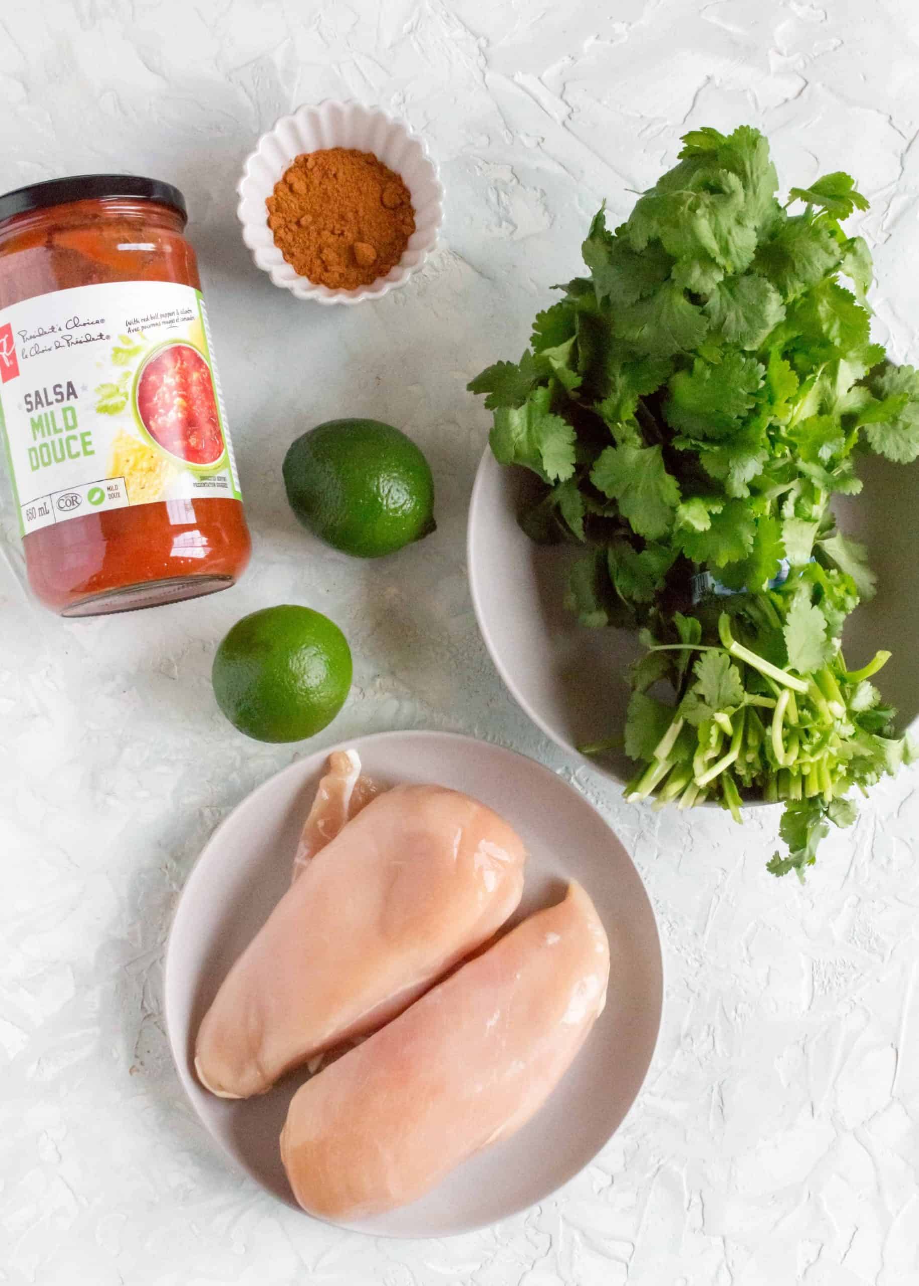 ingredients for slow cooker shredded chicken flatly: chicken, salsa, lime, taco seasoning, cilantro