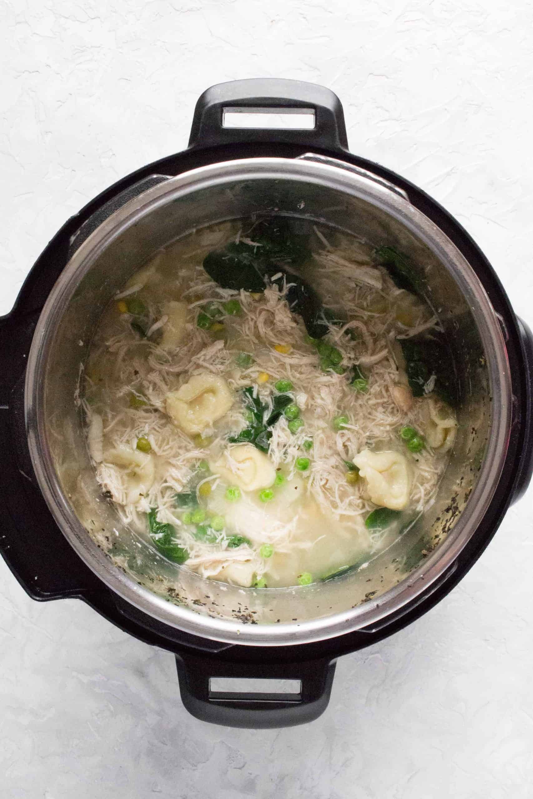 instant pot with cooked chicken and tortellini soup inside