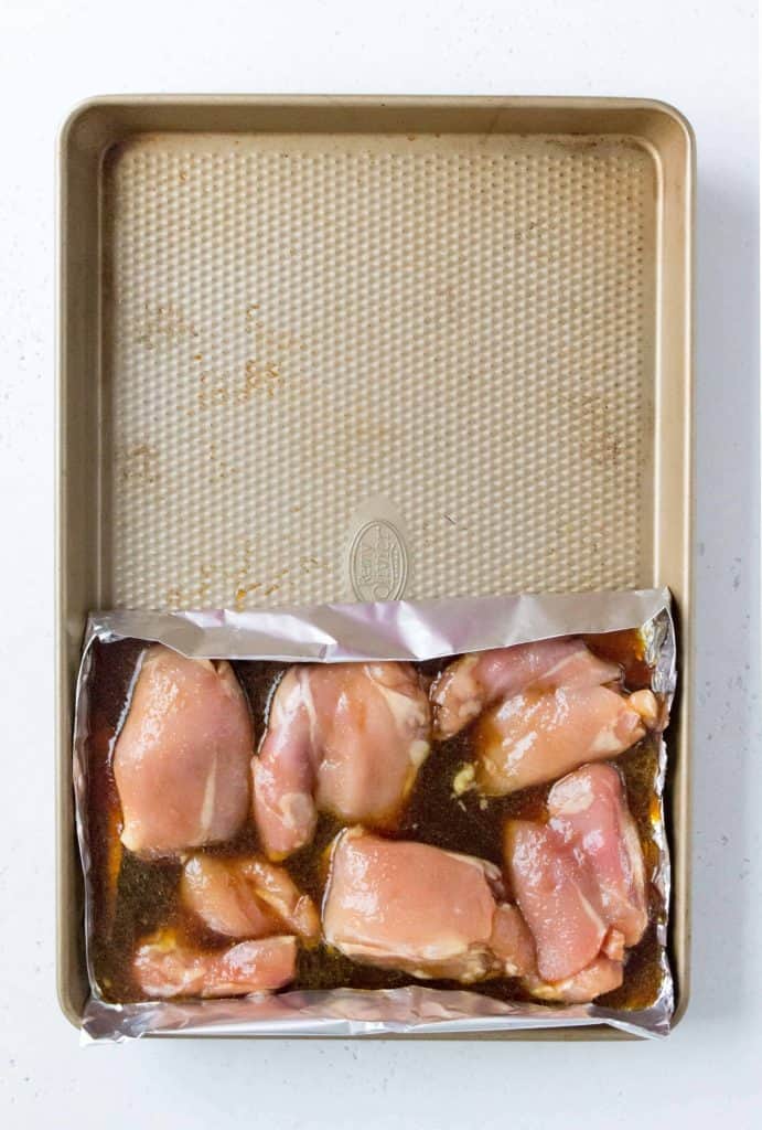 sheet pan with tin foil keeping the chicken thighs on half the sheet