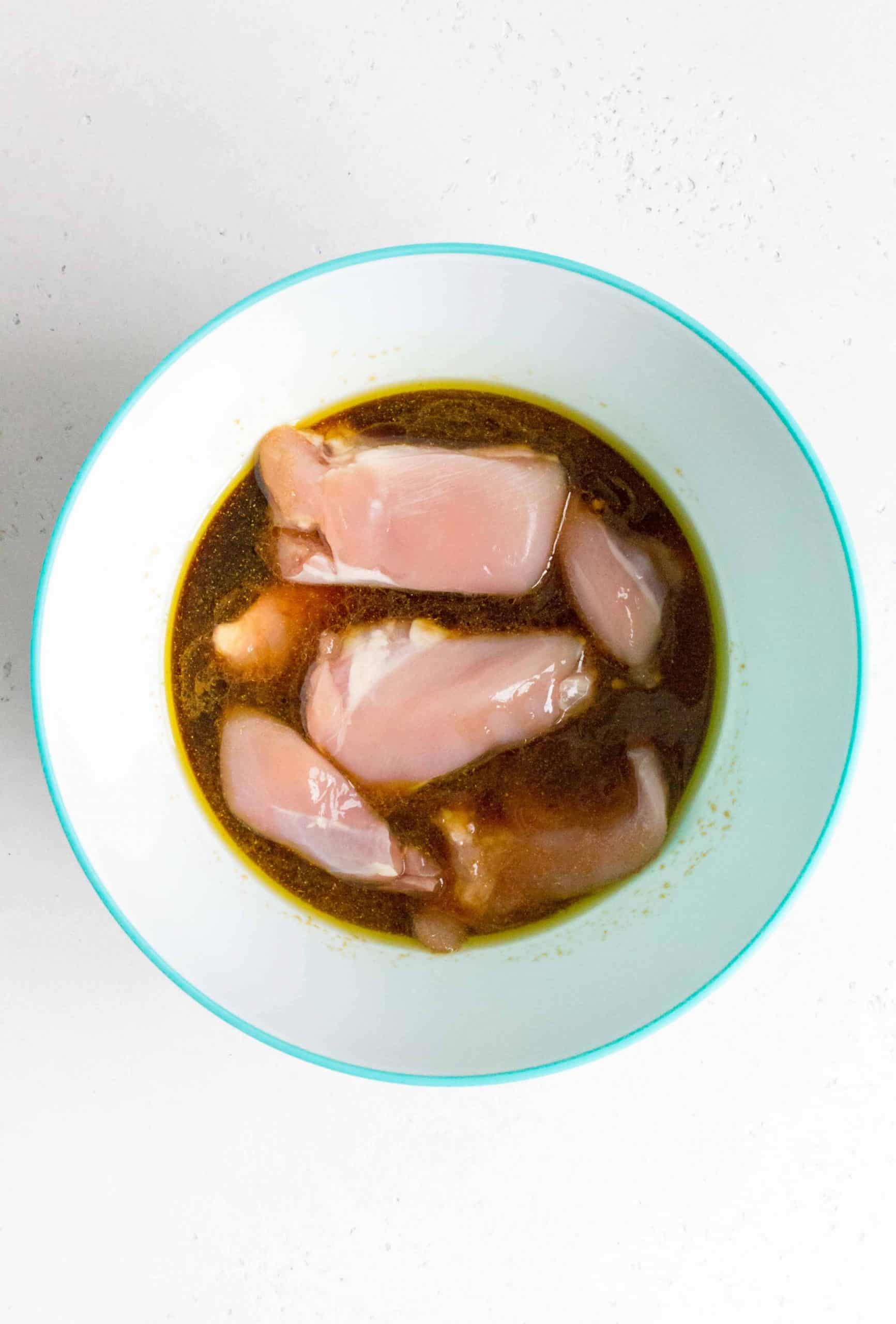 Chicken marinating in honey soy sauce in a bowl. 