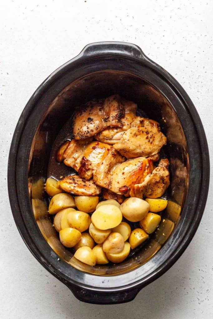 Slow cooker with chicken thighs and potatoes with honey garlic.