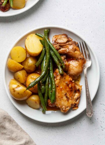 A plate of slow cooker chicken and potatoes with green beans.