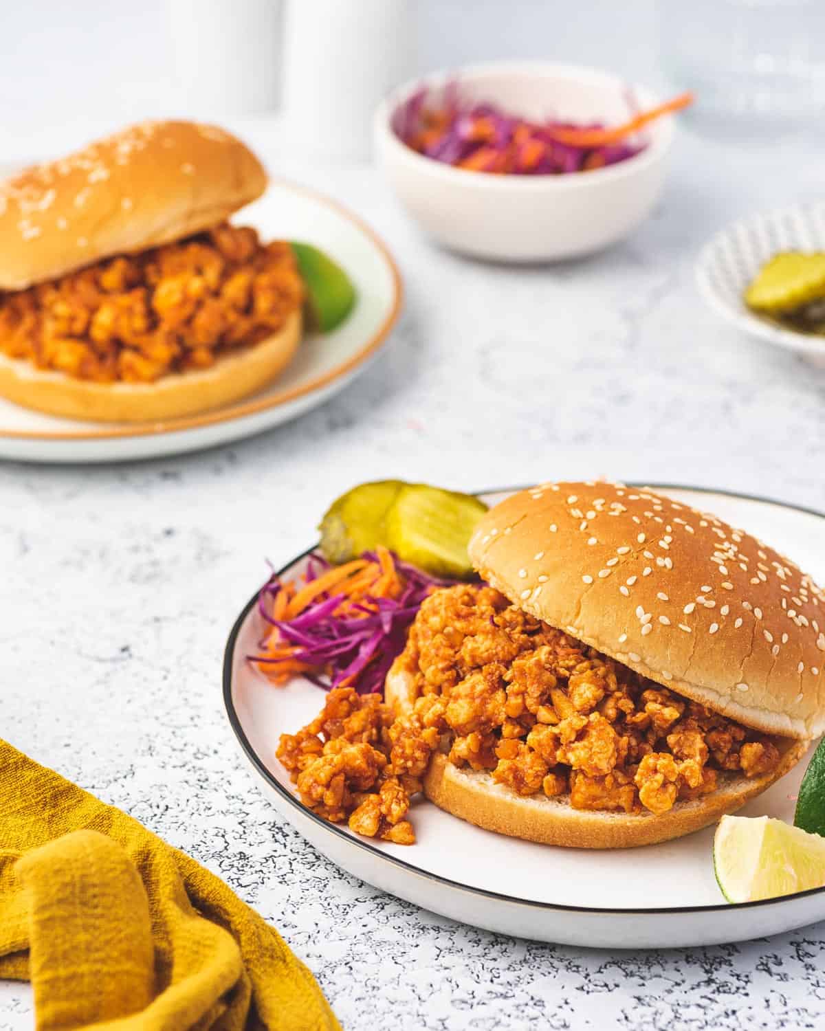 Two plates of chicken sloppy joes in a burger bun.