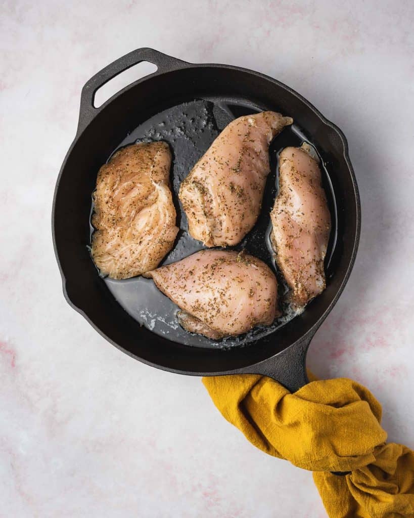 Chicken breasts added into a cast iron.
