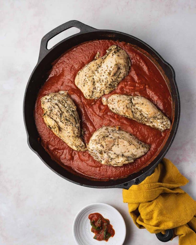 Chicken breasts added to tomato sauce.