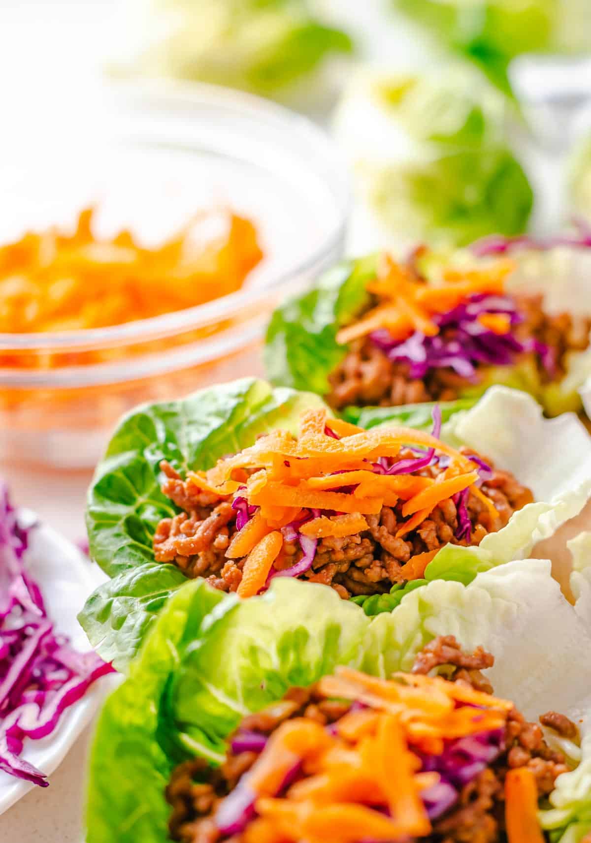 Profile view of three lettuce wraps with ground beef with one in the middle, in focus.