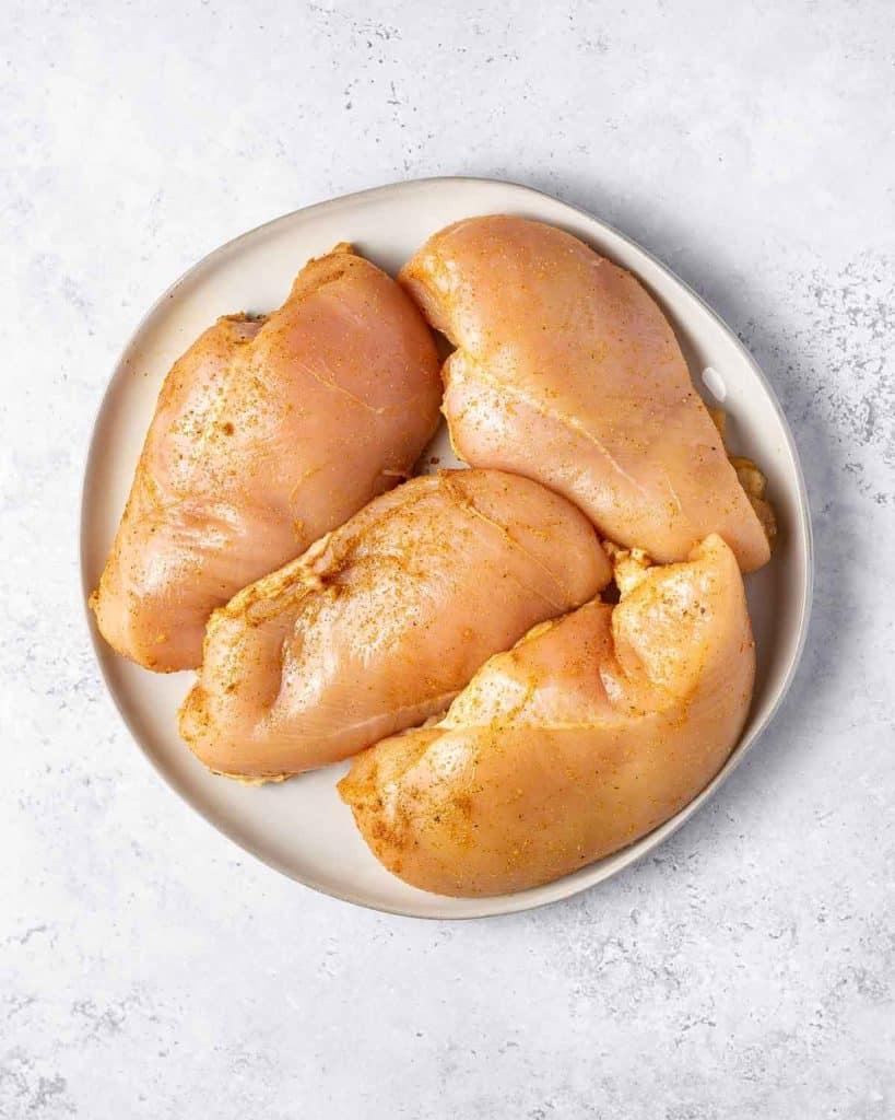 Chicken breasts seasoning on a plate.