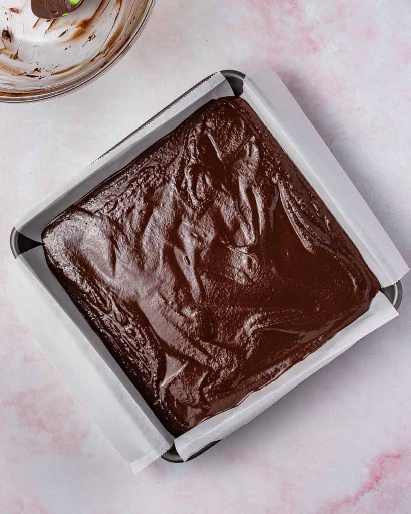 Melted chocolate added to a lined sheet pan.