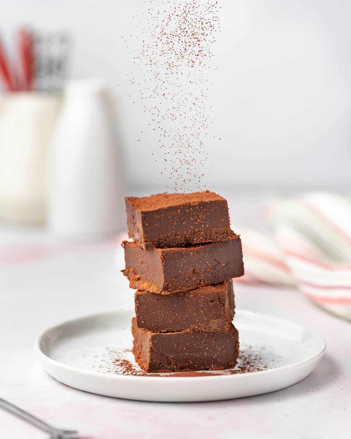 A plate with a stack of nama chocolates with cocoa dusted on top.