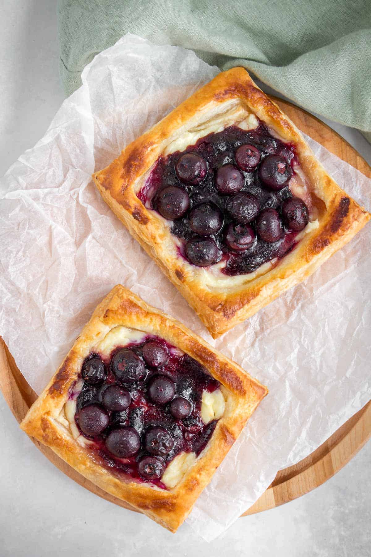 Two blueberry cream cheese danish on a serving board.