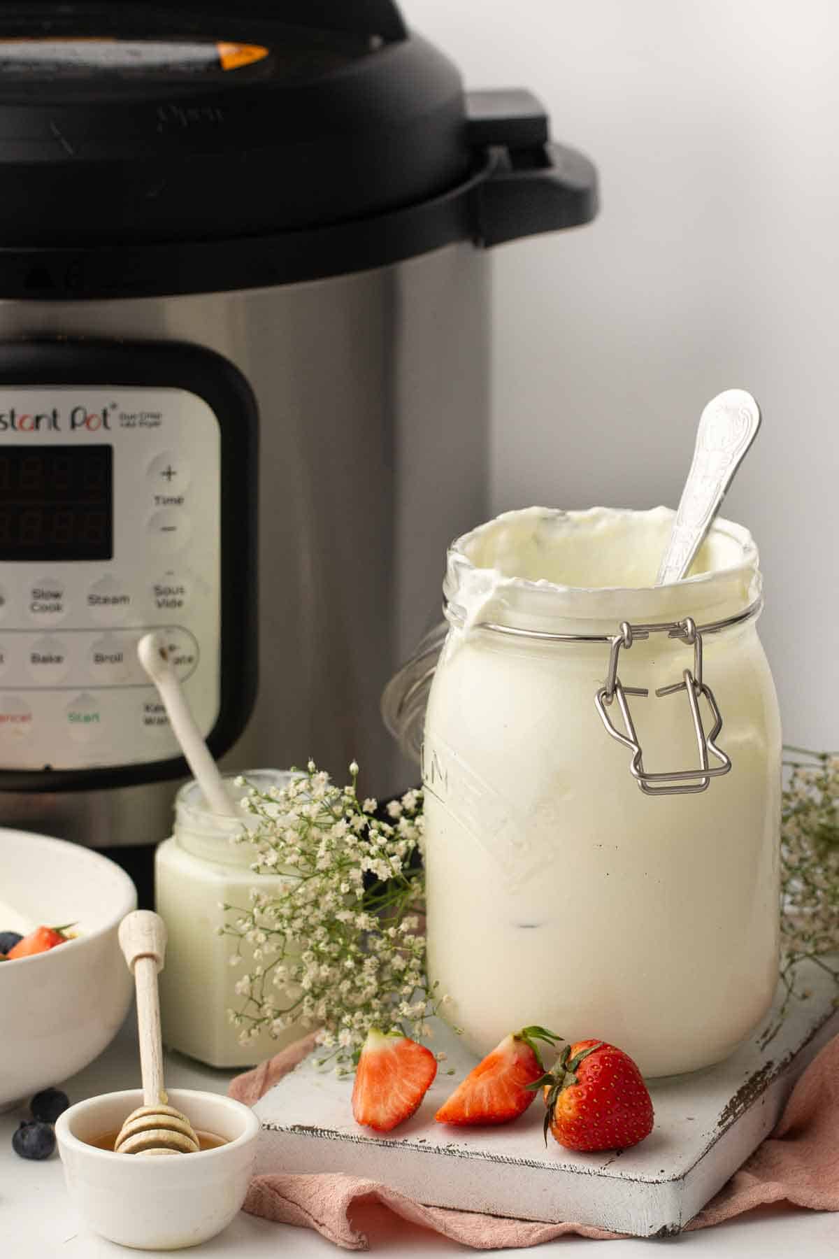 A jar of yogurt beside an instant pot.