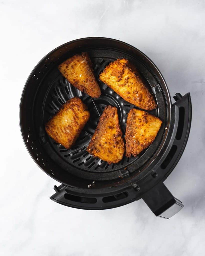 Air fryer basket with air fried fish.