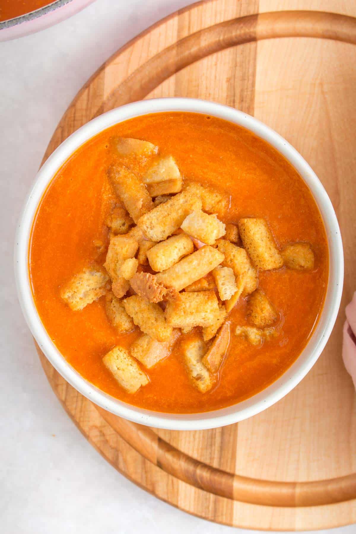 Overhead view of a bowl of bacon tomato soup with croutons.
