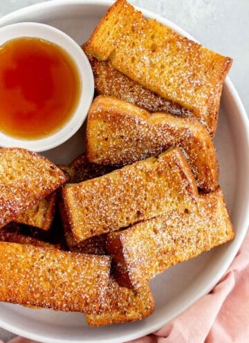 Close up of air fryer french toast sticks with powdered sugar dusted on top.