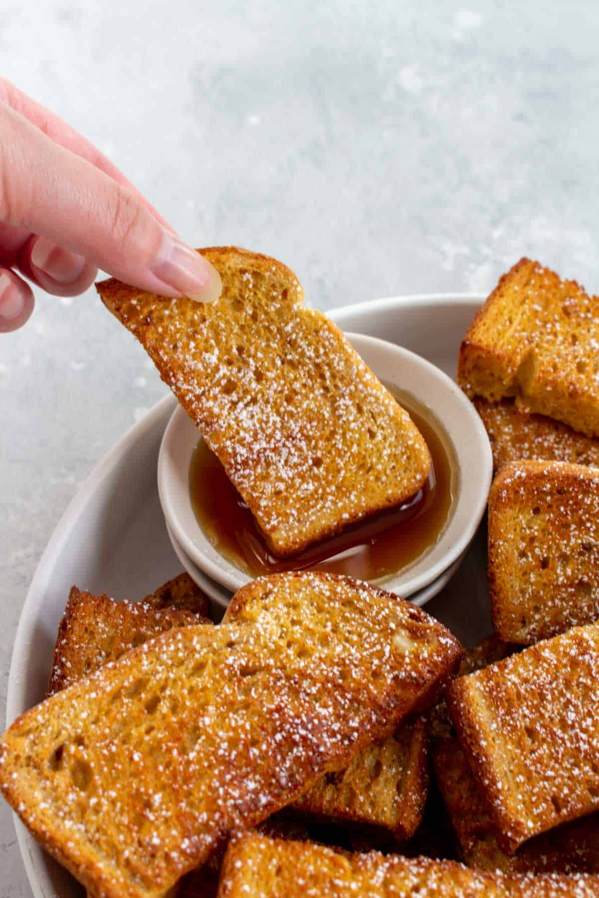 A air fryer french toast sticks dipped into maple syrup.