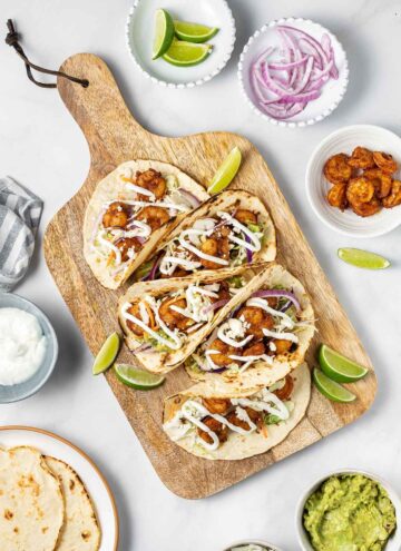 A serving board with five air fryer shrimp tacos.