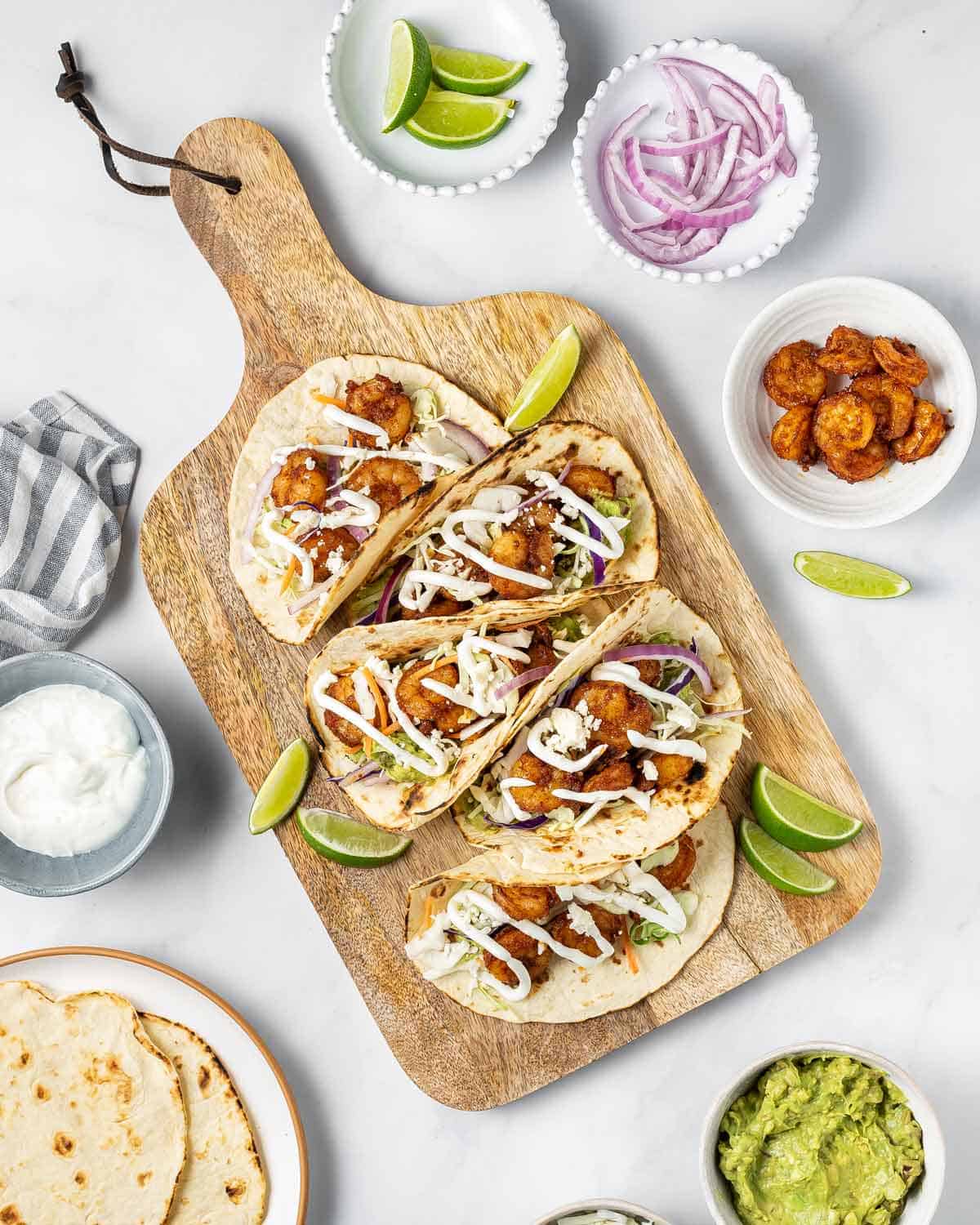 A serving board with five air fryer shrimp tacos.