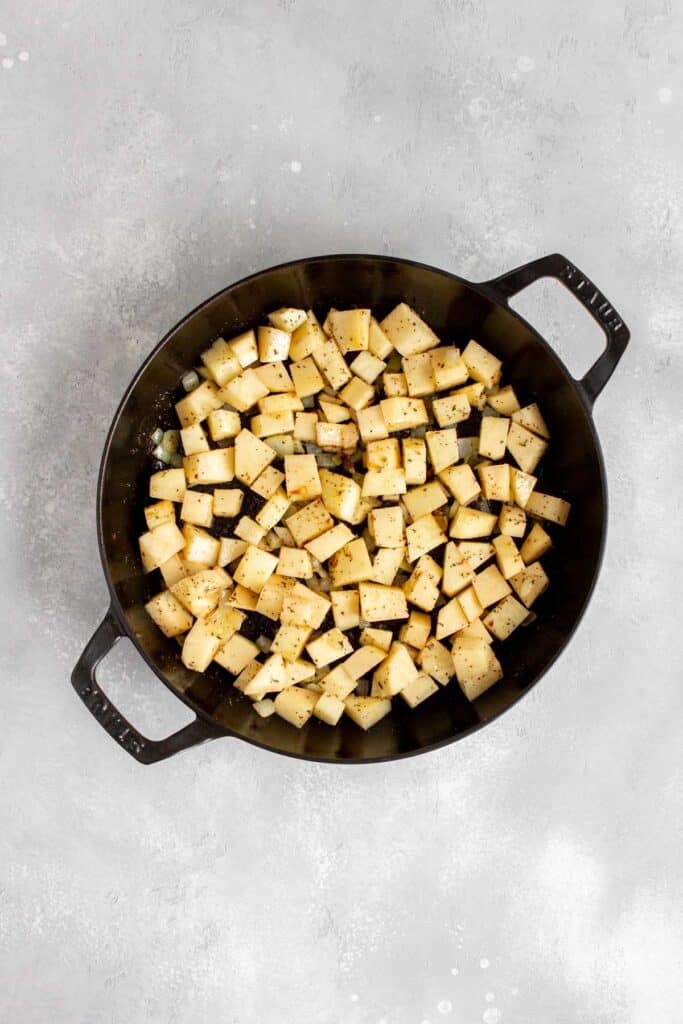Seasoned potato cubes added to the pan.
