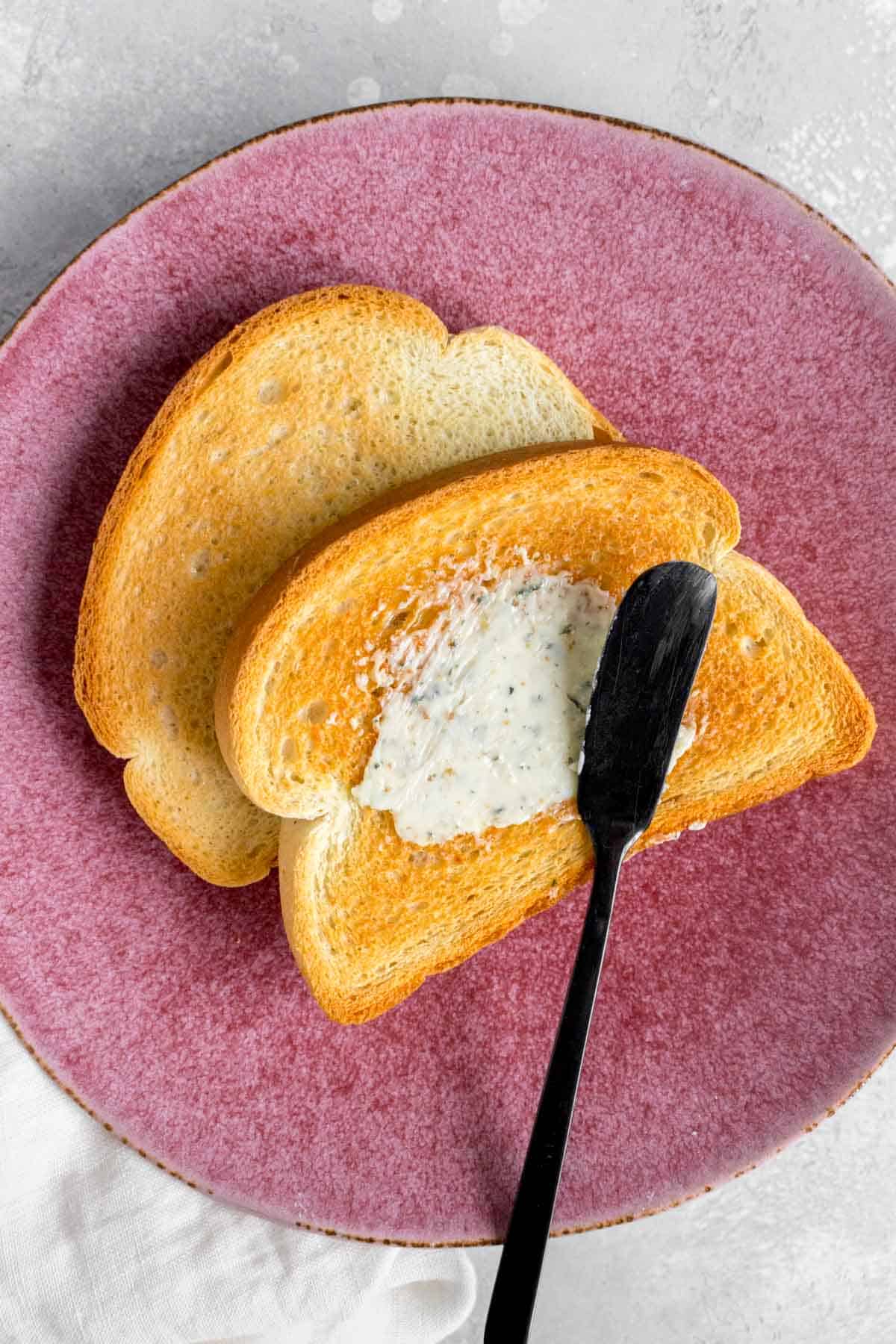 Close up of buttered toast on a pink plate.