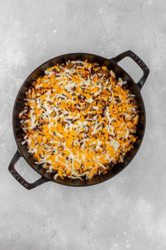 Melted cheese over taco beef in a pan.