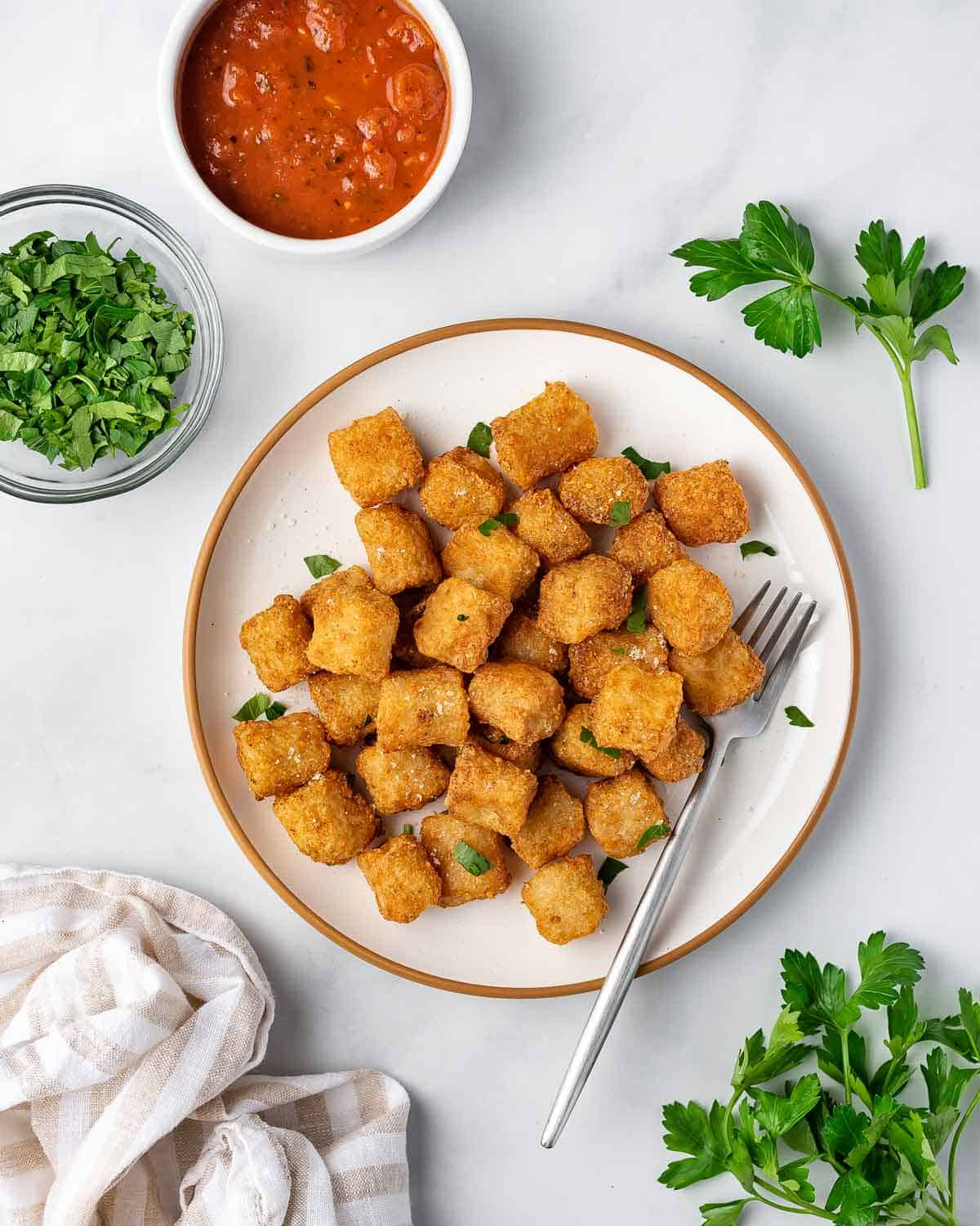 A plate of air fryer cauliflower gnocchi with fresh herbs scattered on top.