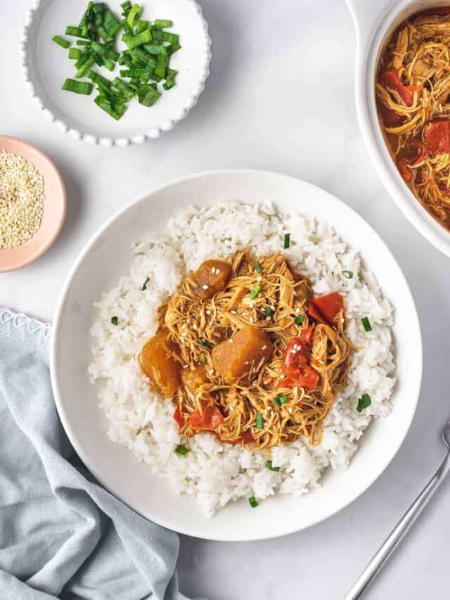Overhead view of a plate of rice with crockpot pineapple chicken on top.