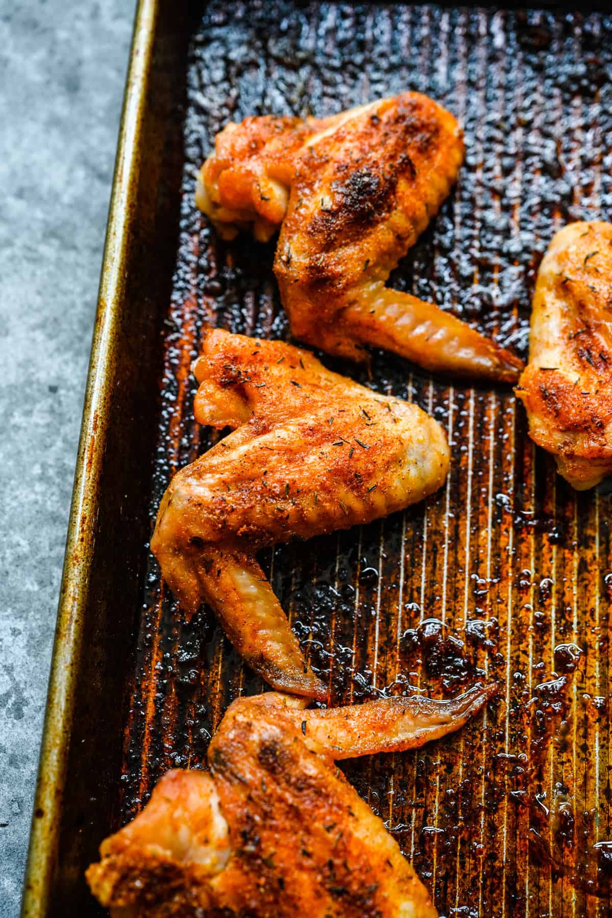 Three baked chicken wings on a sheet pan.