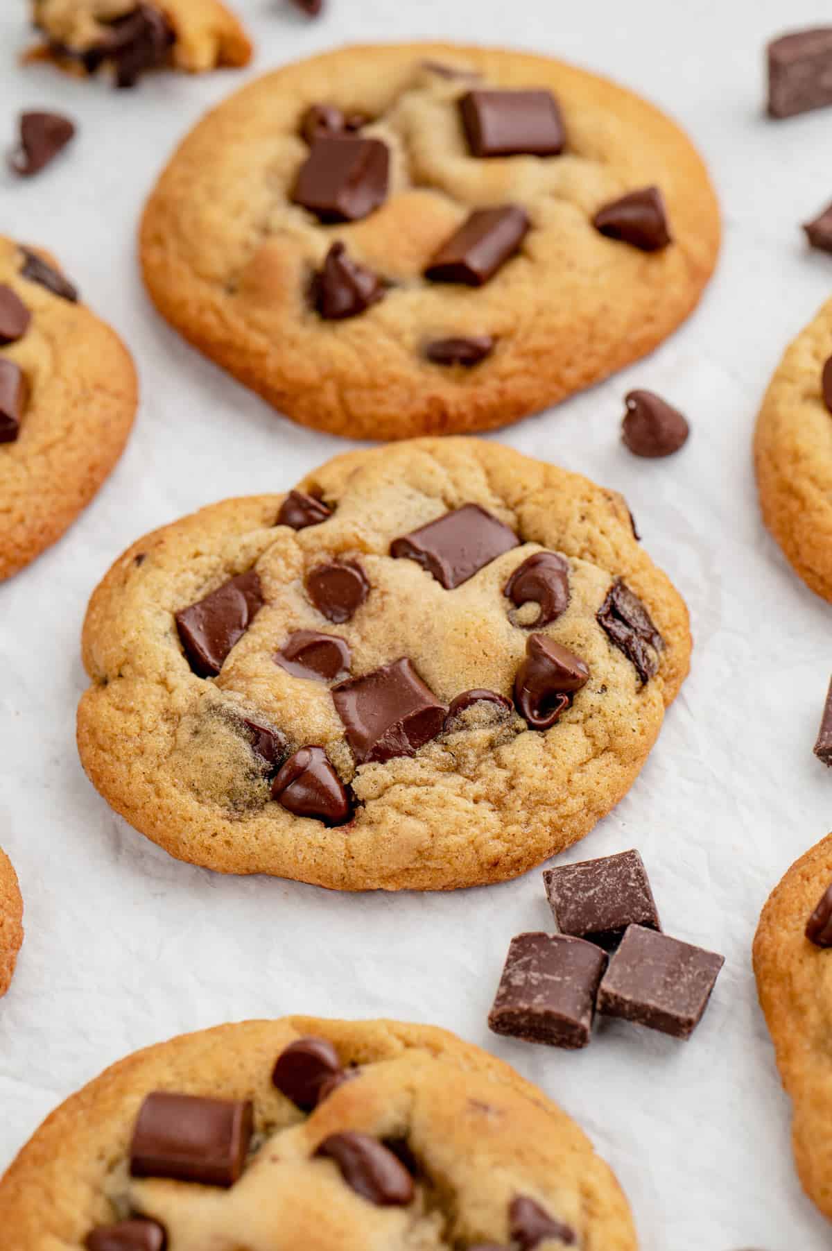 Multiple chocolate chunk cookies on a parchment sheet.
