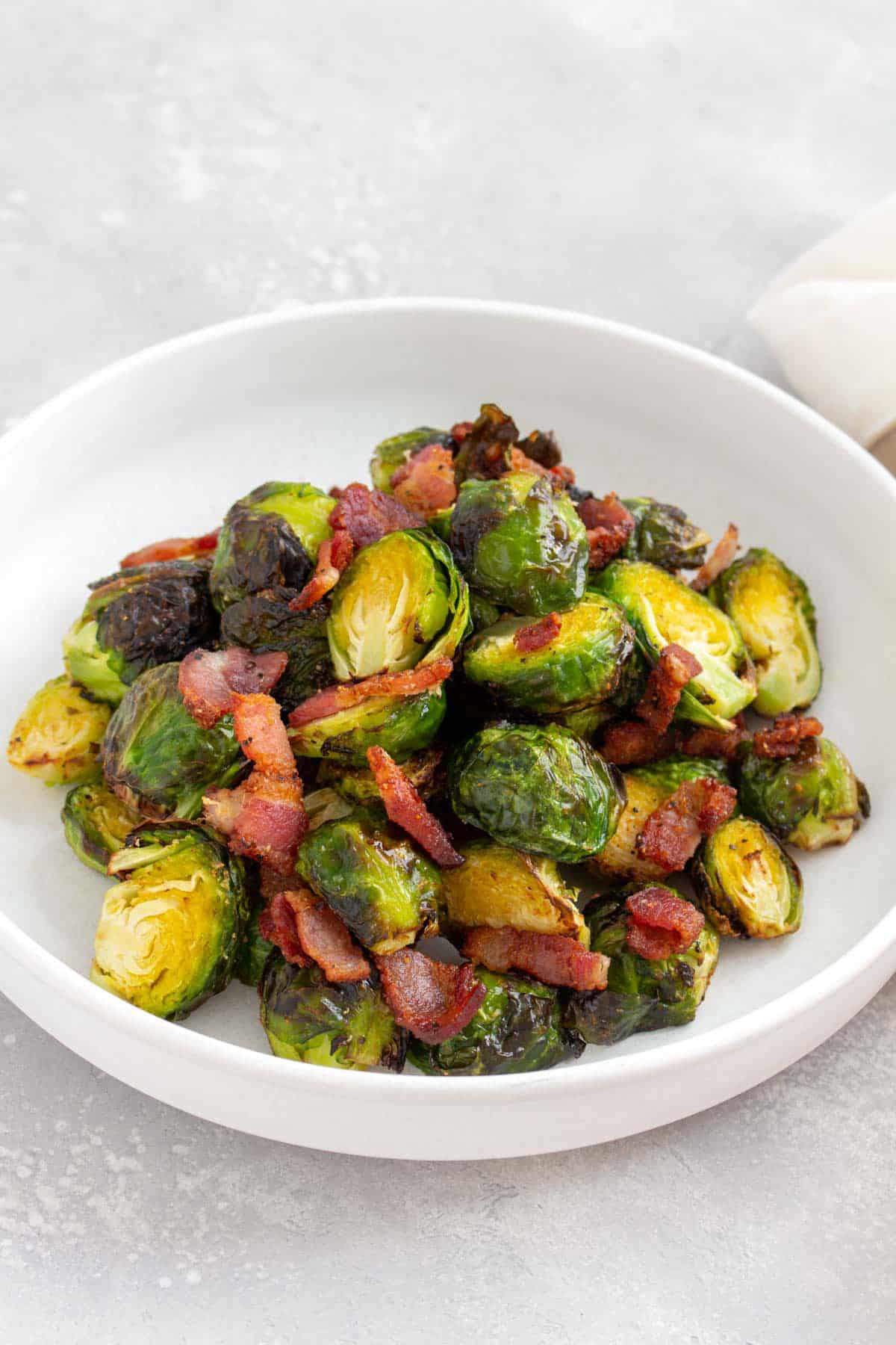 An angled view of a plate of air fryer brussels sprouts and bacon.