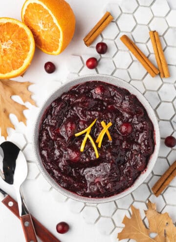 Overhead view of a bowl of slow cooker cranberry sauce with orange zest as garnish.