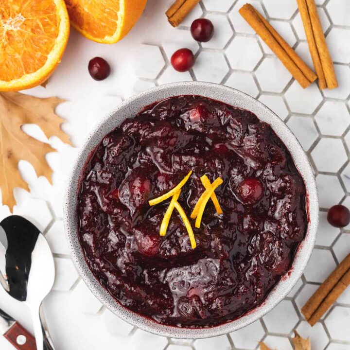 Overhead view of a bowl of slow cooker cranberry sauce with orange zest as garnish.