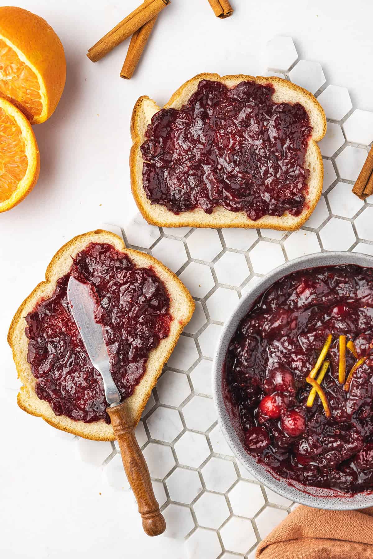 Overhead view of two slices of bread with cranberry sauce spread on them.
