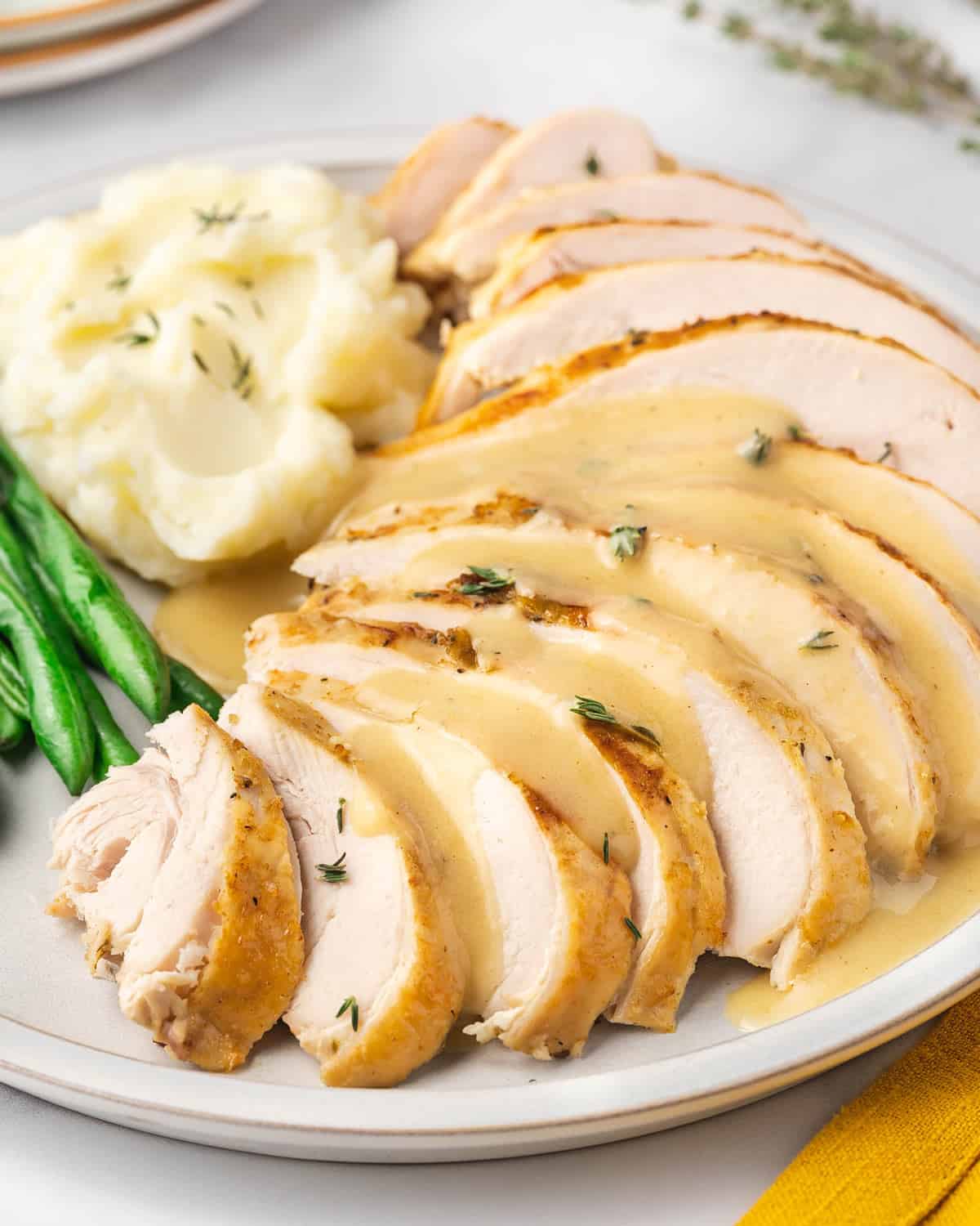 A plate of sliced turkey breasts with gravy over top.