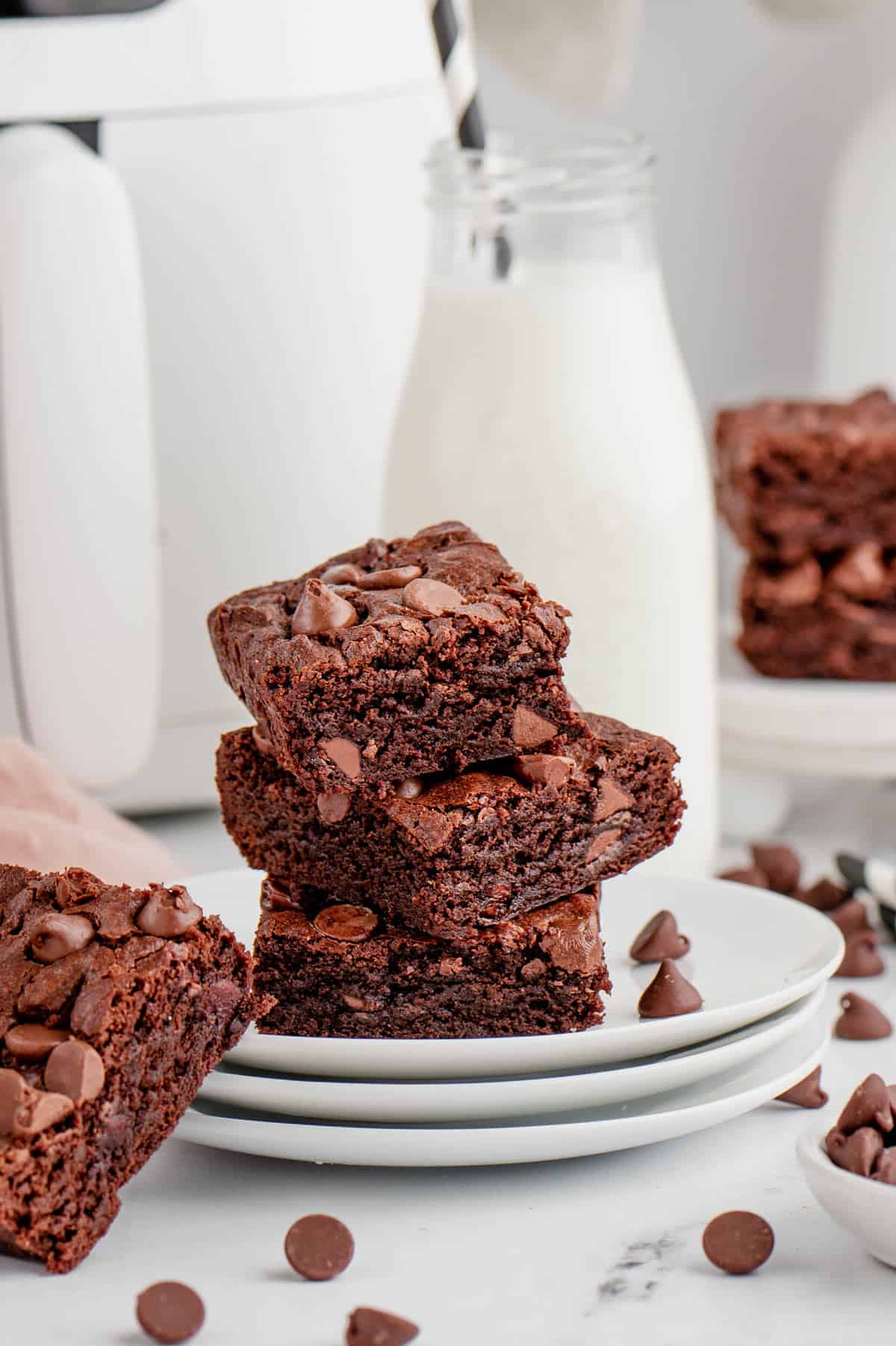 Three pieces of air fryer brownies stacked on top of each other with milk in the background.