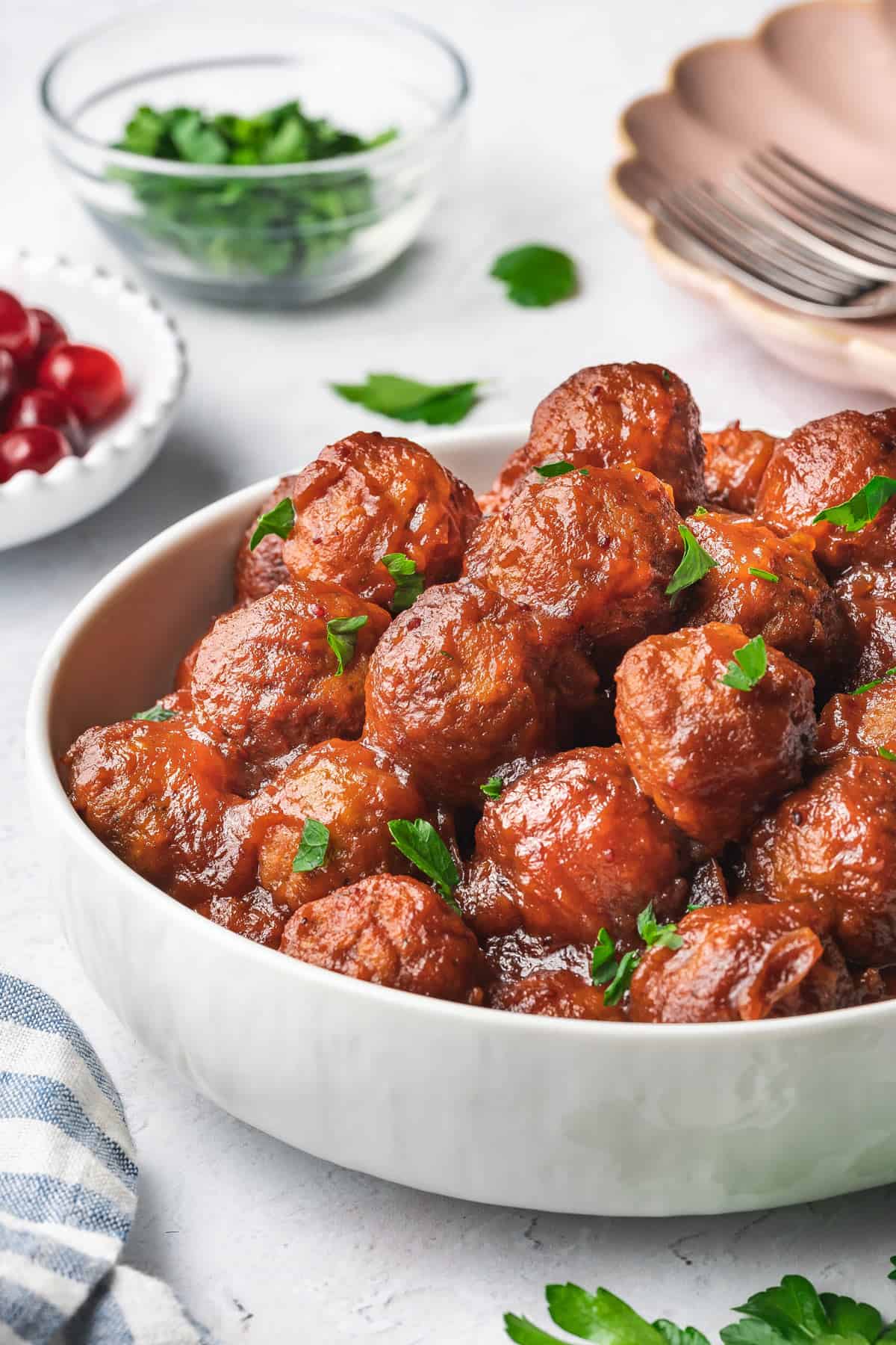 A bowl of slow cooker cranberry meatballs on top with fresh parsley garnish.