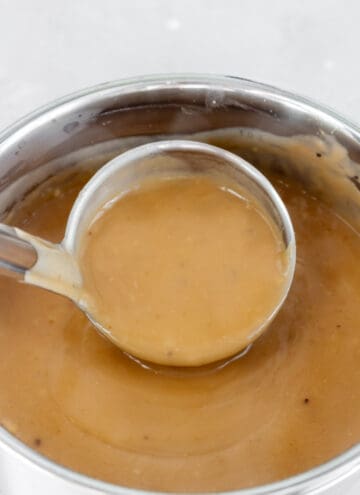 A pot of gravy being scooped.
