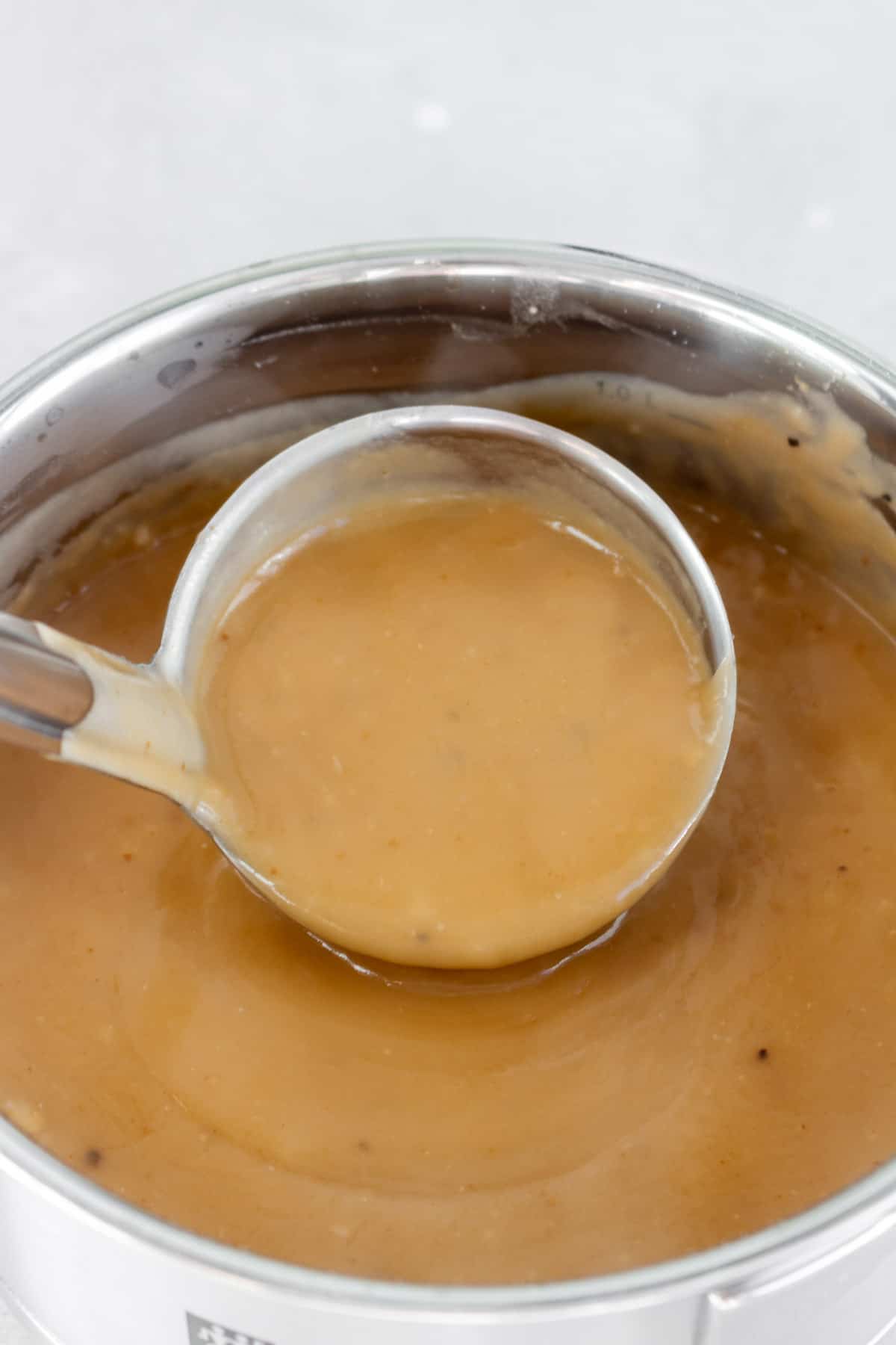 A pot of gravy being scooped.