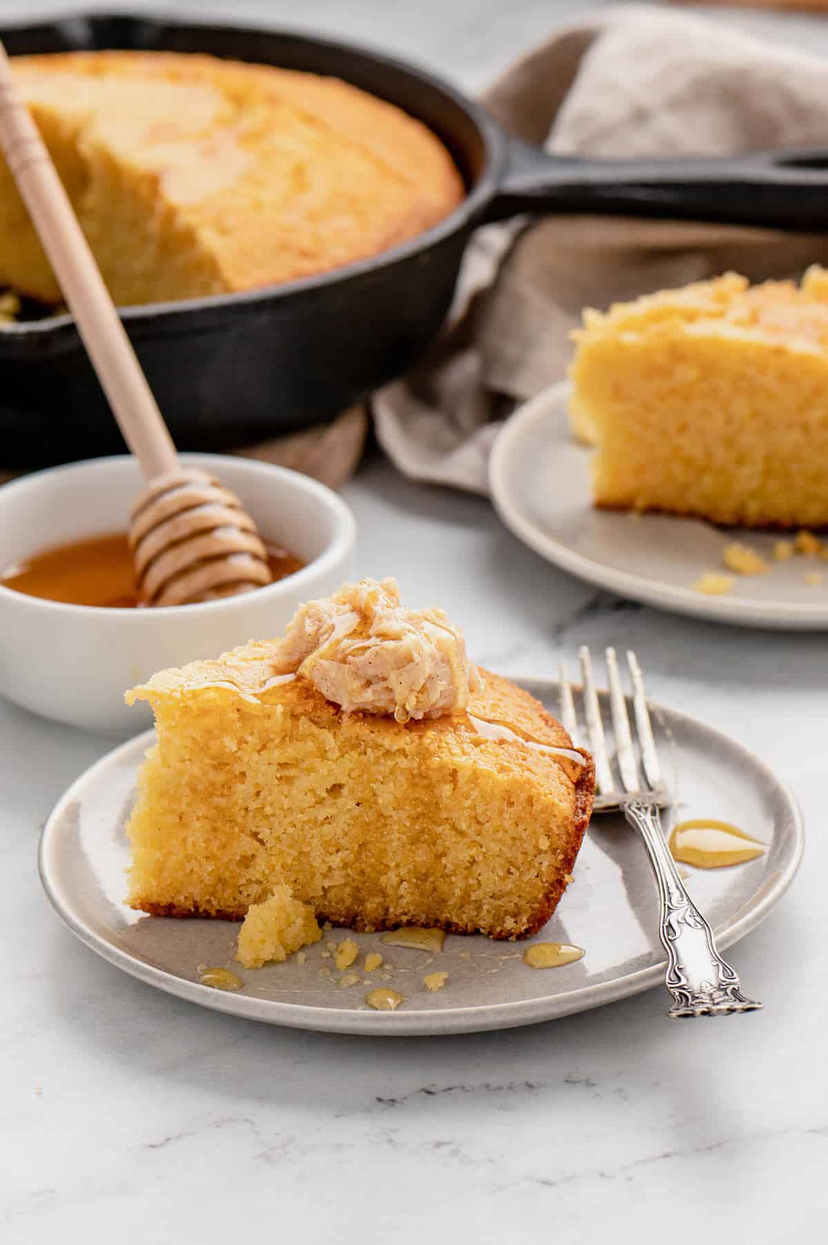 Profile view of a slice of cornbread on a plate with a fork.
