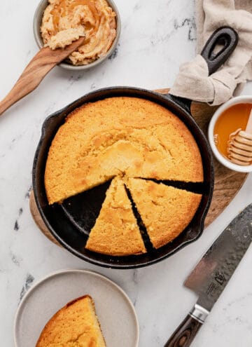 Overhead view of a skillet cornbread with a slice cut out and two more sliced.