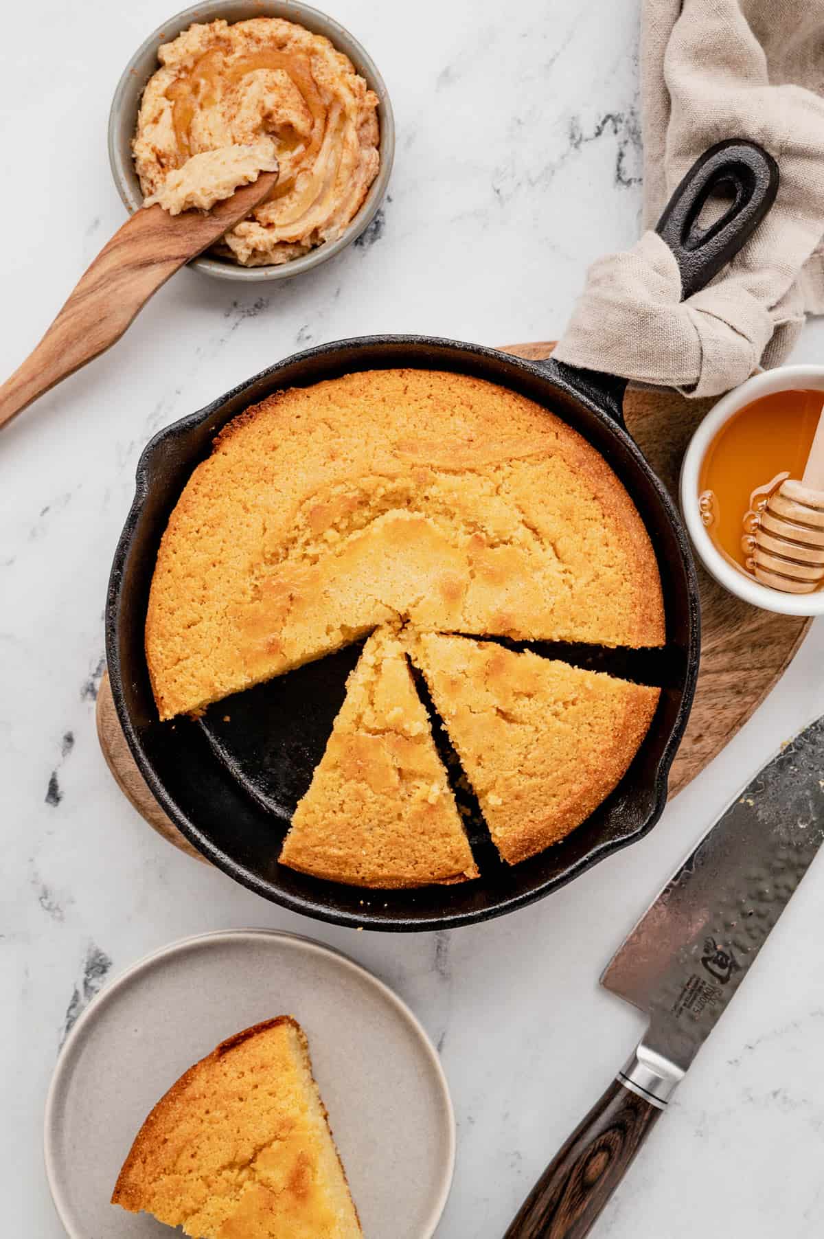 Overhead view of a skillet cornbread with a slice cut out and two more sliced.