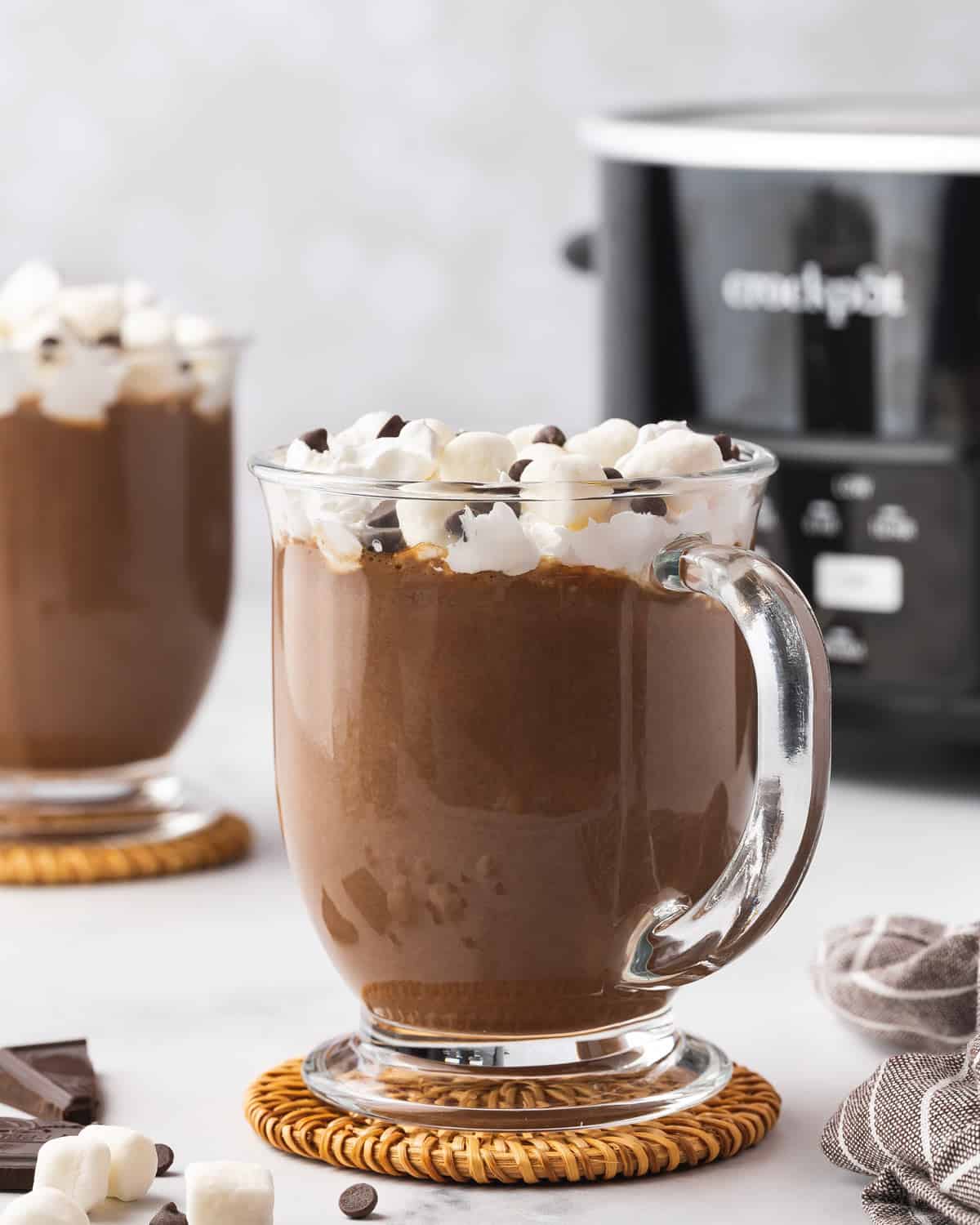 A mug of crockpot hot chocolate with whipped cream, marshmallows, and chocolate chips.