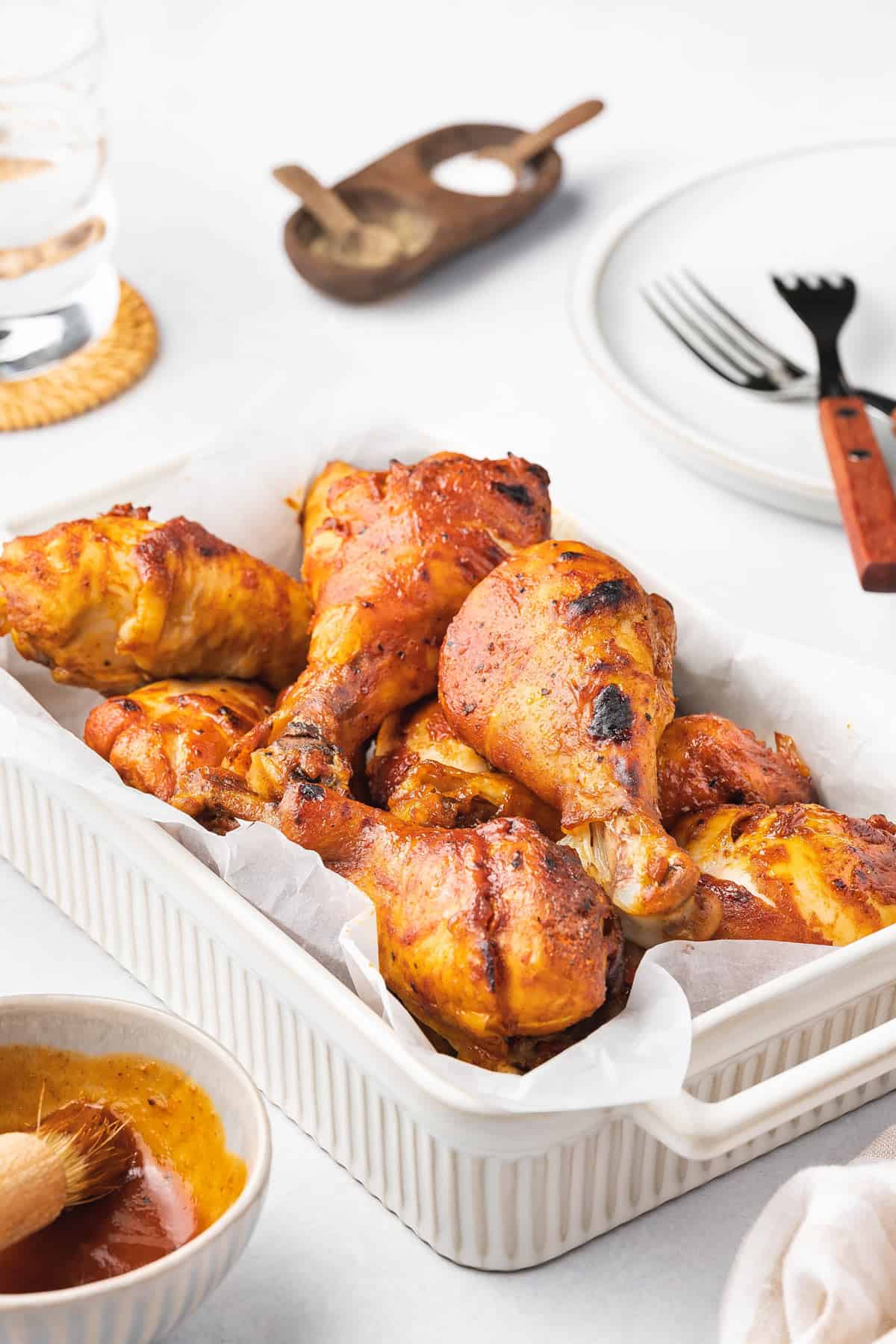 A baking dish with multiple slow cooker BBQ chicken drumsticks.