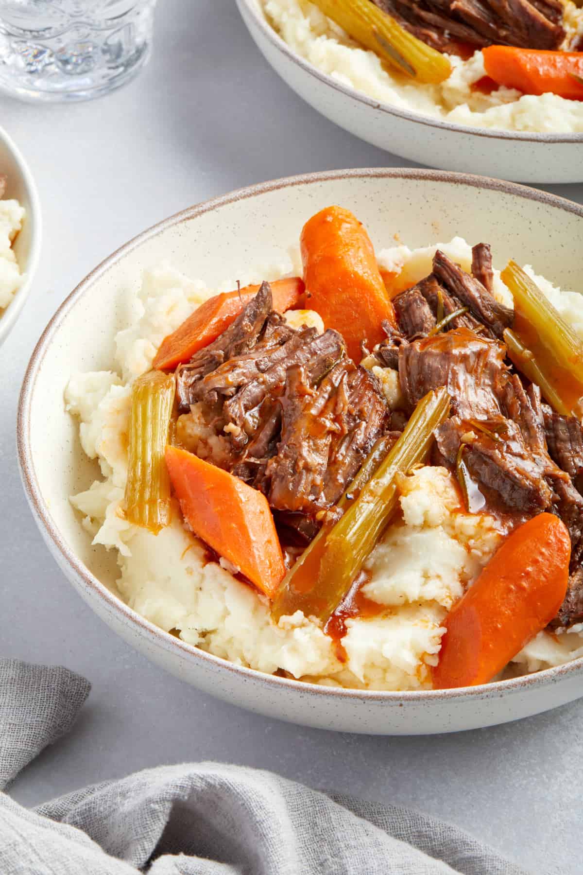 Close up view of a plate of mashed potatoes with dutch oven pot roast on top.