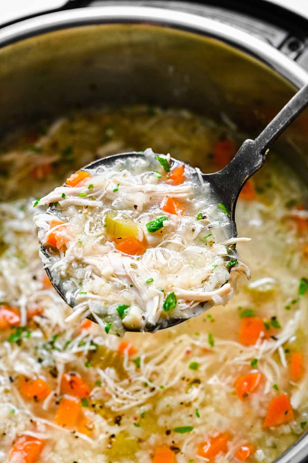 A ladle of chicken and rice soup lifted from the instant pot.