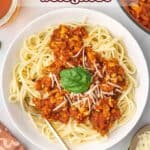 Pinterest graphic of a plate of ground chicken bolognese over spaghetti noodles.