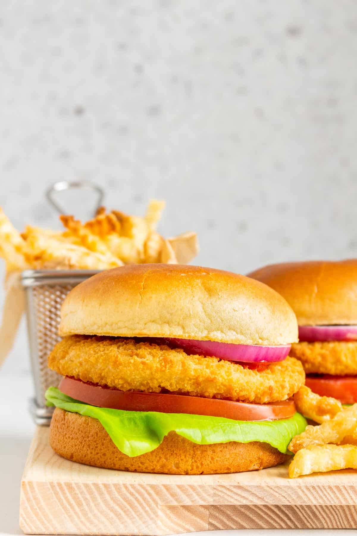 An air fryer crispy chicken sandwich surrounded by fries.
