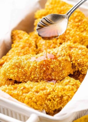 A spoonful of hot honey drizzled over crispy chicken tenders.
