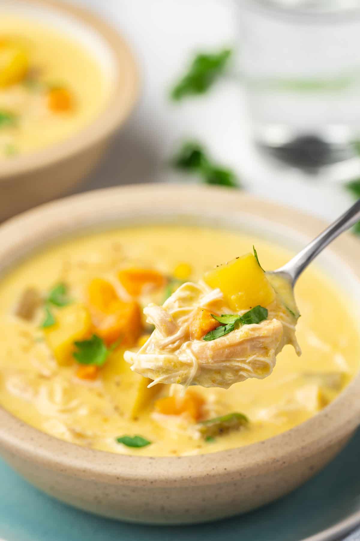A spoonful of slow cooker chicken and corn soup lifted from the bowl of soup.