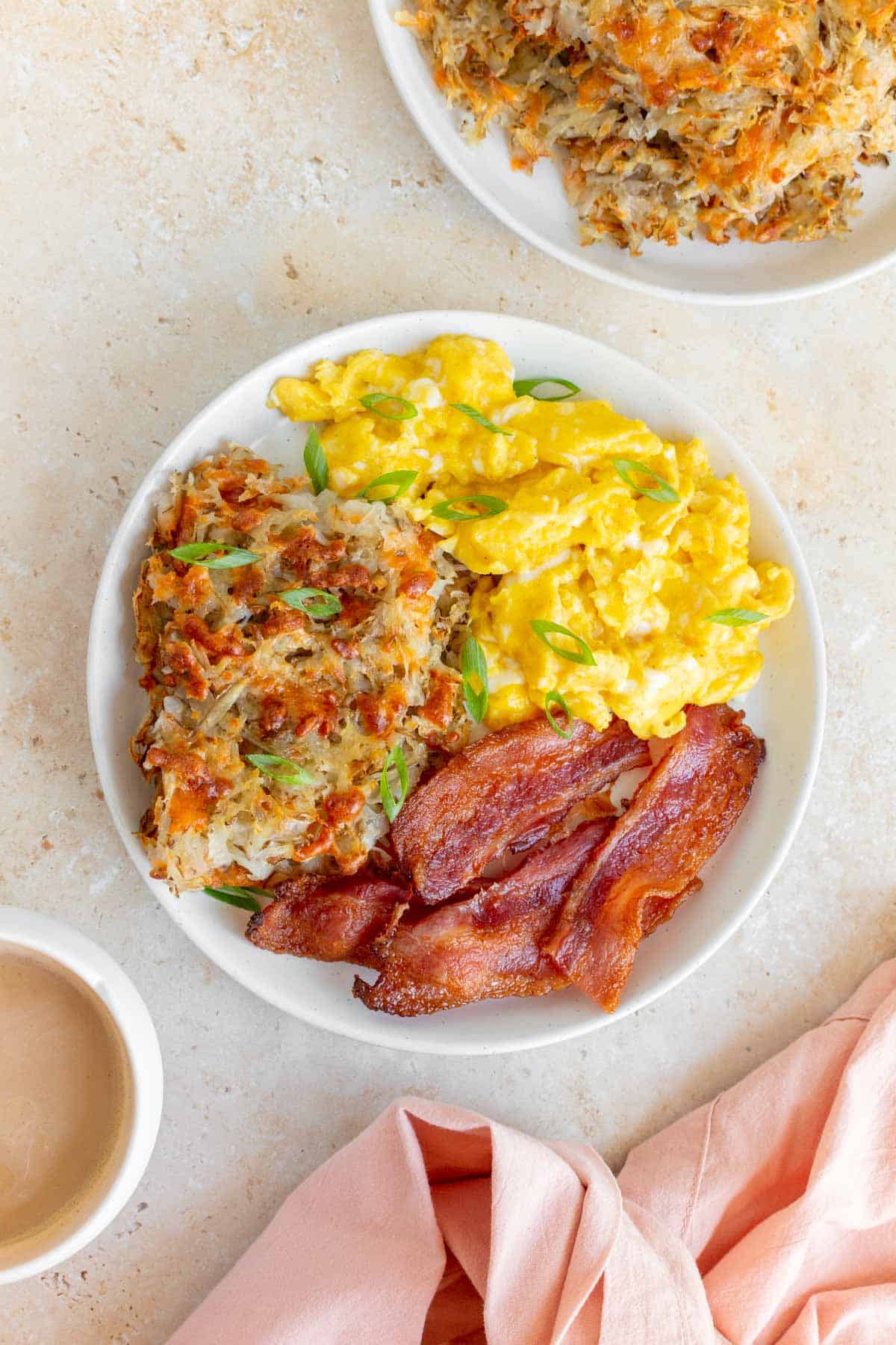 A plate with sheet pan hash browns, scrambled eggs, and bacon.