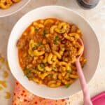 A bowl of one pot homemade hamburger helper with a pink spoon touched in.